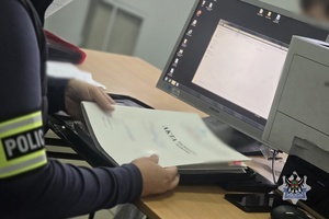Na zdjęciu policjant przygotowuje dokumentację służbową.