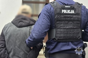 Na zdjeciu policjant zakłada kajdanki zatrzymanej osobie.