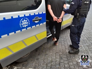 Policjant wprowadza zatrzymanego do radiowozu