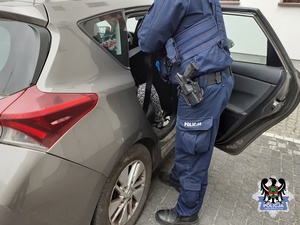 umundurowany policjant przy nieoznakowanym radiowozie