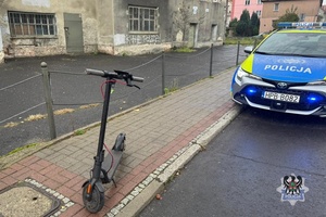 Na zdjęciu hulajnoga elektryczna oraz samochód.