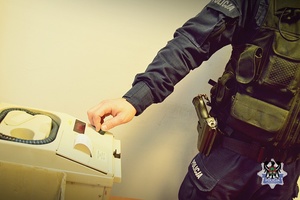 Na zdjeciu policjant przygotowuje urządzenie do badania stanu trzeźwości.
