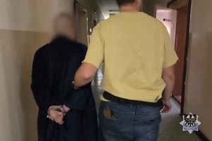 Na zdjęciu policjant prowadzi zatrzymanego mężczyznę.