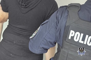 Na zdjęciu policjant pilnuje zatrzymanej kobiety.