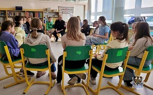 Na zdjęciu policjant oraz uczniowie szkoły podstawowej podczas zajęć.