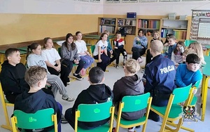 Na zdjęciu policjant oraz uczniowie szkoły podstawowej podczas zajęć.