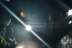 Na zdjęciu policjant sprawdza oświetlenie pojazdu