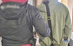 Na zdjęciu policjant pilnuje zatrzymanego mężczyzny.