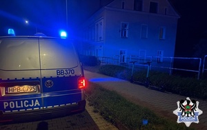 zdjęcie przedstawia policyjny radiowóz w nocy z włączonymi sygnałami świetlnymi