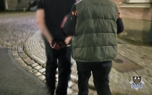 Na zdjęciu nieumundurowany policjant prowadzi zatrzymanego mężczyznę.