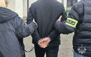 Na zdjęciu policjant zakłada kajdanki zatrzymanemu mężczyźnie.