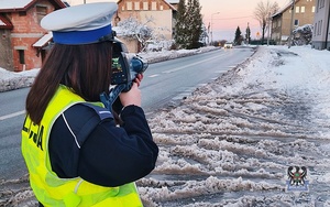 Na zdjęciu policjantka podczas ręcznego pomiaru prędkości .