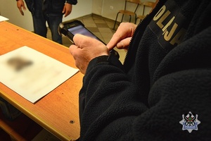 Na zdjęciu policjant sprawdza zatrzymanego meżczyznę w policyjnych systemach.