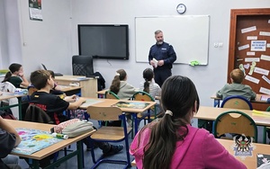 Na zdjęciu policjant w trakcie pogadanki z dziećmi ze szkoły w Jugowicach.