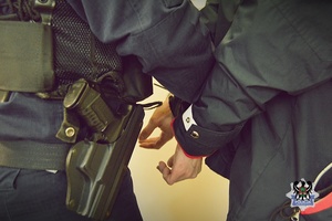 Na zdjęciu policjant zakłada kajdanki zatrzymanemu.