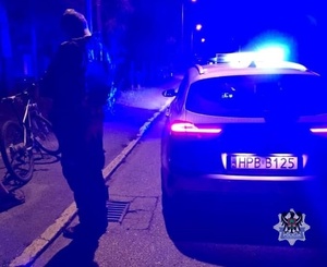Na zdjęciu radiowóz policjant oraz rower w porze nocnej.