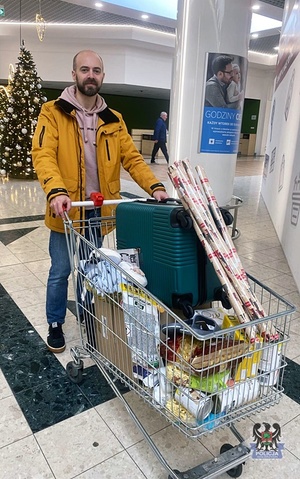 Na zdjęciu policjant podczas zakupów z koszykiem sklepowym.