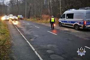 Kontrola na drodze policjant, radiowóz policyjny i auta poruszające się po jezdni