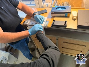 na zdjęciu policjant wykonuje daktyloskopie zatrzymanemu