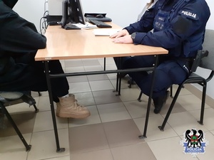Na zdjęciu zatrzymana kobieta podczas przesłuchania z umundurowanym policjantem
