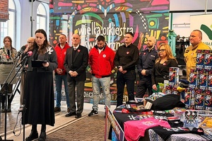 Na zdjęciu policjant w grupie osób podczas konferencji prasowej.
