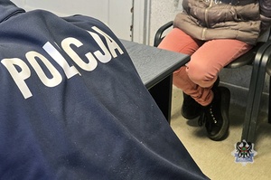 Na zdjęciu policjant pilnuje zatrzymanej kobiety.