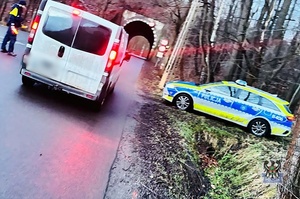 Na zdjęciu policjant, radiowóz oraz przykładowy kontrolowany samochód.