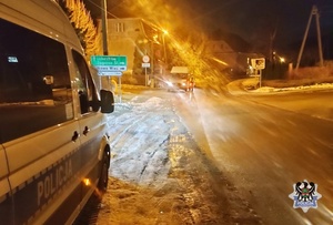 Na zdjęciu radiowóz oraz policjant kontrolujący kierującego.