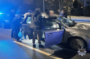 Na zdjęciu policjanci wykonują czynności z zatrzymanymi mężczyznami przy kontrolowanym samochodzie.