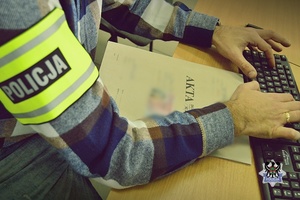Na zdjęciu policjant i akta sprawy.