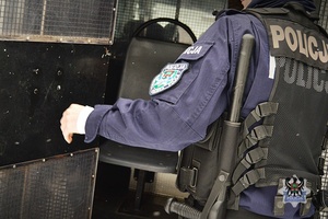 Na zdjęciu policjant zamyka drzwi radiowozu.