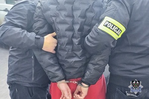 Na zdjęciu policjant zakłada kajdanki zatrzymanemu.