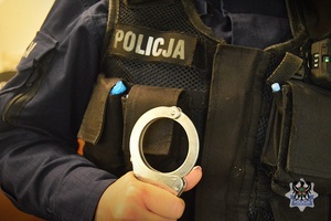 Na zdjęciu policjant trzymający  kajdanki