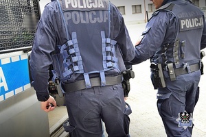 Na zdjęciu policjanci umieszczają zatrzymanego w radiowozie.