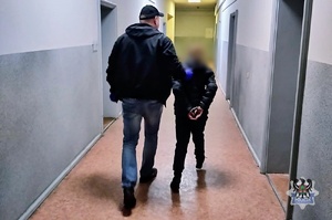 Na zdjęciu policjant prowadzi poszukiwana kobietę.