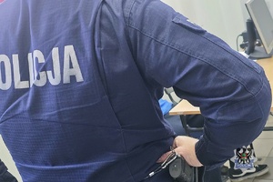 Na zdjęciu policjant pilnuje zatrzymanego mężczyzny.