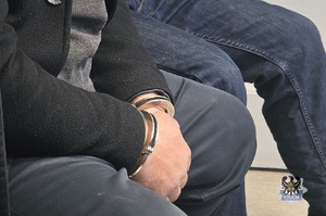 Na zdjęciu zatrzymani mężczyźni w kajdankach.