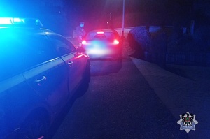 Na zdjęciu policyjny radiowóz w porze nocnej oraz kontrolowany samochód.