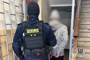 Na zdjęciu policjanci prowadzi meżczyznę do celi.