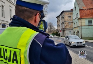 Na zdjęciu policjant podczas ręcznego pomiaru prędkości.
