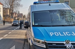 Na zdjęciu policyjny radiowóz oraz policjanci kontrolujący trzeźwość kierujących.