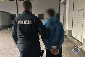 Na zdjęciu policjant prowadzi zatrzymanego mężczyznę.