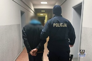 Na zdjęciu policjant prowadzi zatrzymanego mężczyznę.