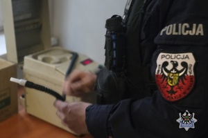 Na zdjeciu policjant obsługuje urządzenie do badania stanu trzeźwości.