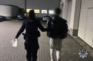 Na zdjęciu policjantka prowadzi zatrzymanego mężczyznę.