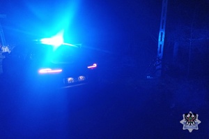 Na zdjęciu rower oraz radiowóz w porze nocnej.