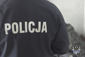 Na zdjęciu policjant pilnuje zatrzymanego.