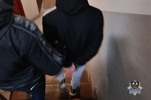 Na zdjęciu policjant prowadzi zatrzymanego mężczyznę.