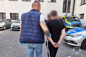 Na zdjęciu policjant prowadzi zatrzymanego.