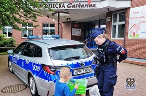 Na zdjęciu policjantka, która przekazuje gry dzieciom.